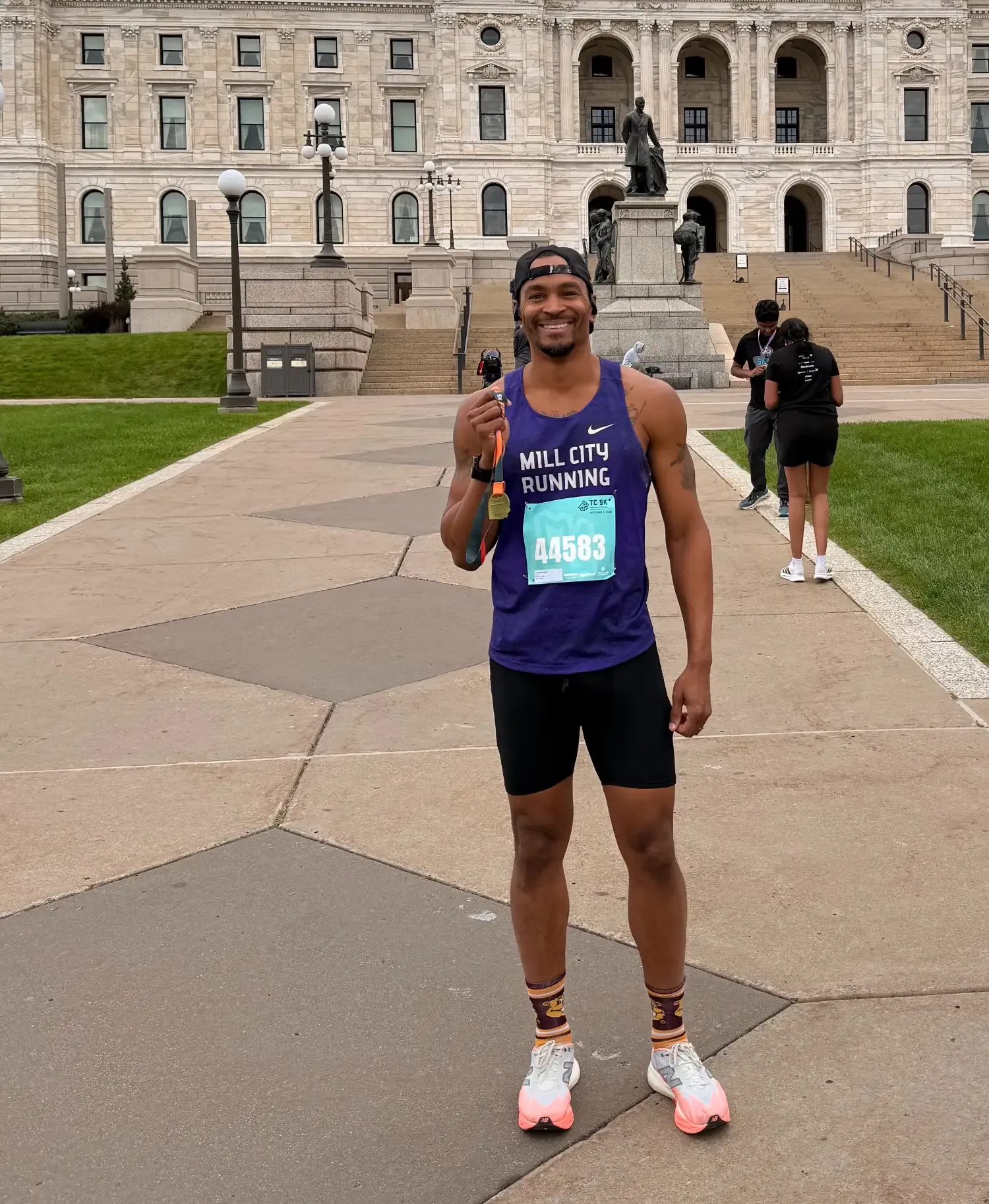 Traek Wells standing in from of the capital building of Saint Paul, holding a 5k finisher medal